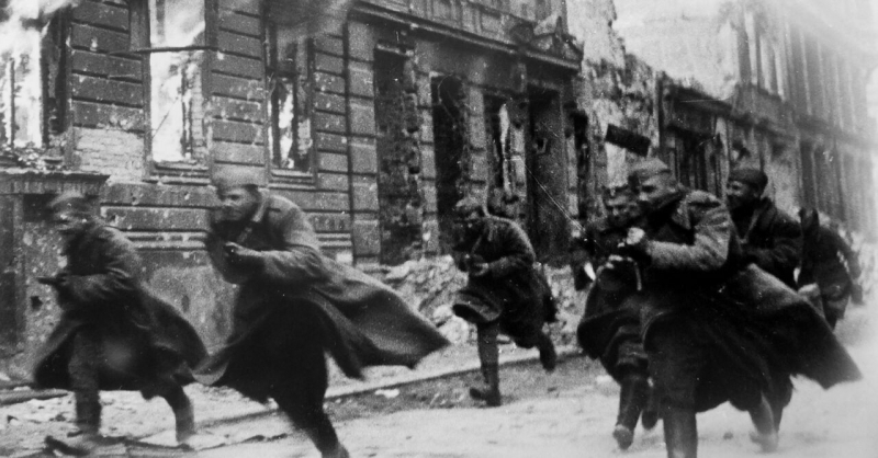 سربازان اتحاد جماهیر شوروی در کنار ساختمانی در حال سوختن در یکی از خیابان های برلین در سال 1945 می دوند.